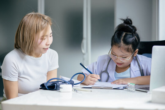 Girl in doctor's uniform examining a patient at a table, Concept Education - Powered by Adobe