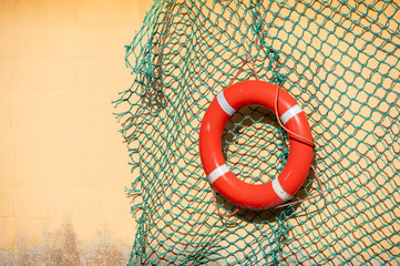 Rettungsring und Fischernetz dekorativ an einer gelben Wand
