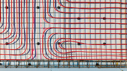 Underfloor heating system with red pipes on construction site, Close-up of underfloor heating installation using red pipes laid on a foundation grid at a building, view of the top