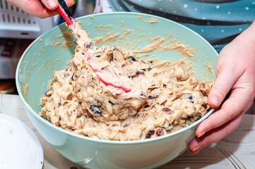 A close-up of cake batter being mixed with a red spatula in a teal bowl.