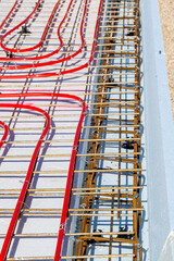 Underfloor heating system with red pipes on construction site, Close-up of underfloor heating installation using red pipes laid on a foundation grid at a building