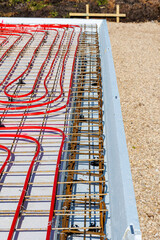 Underfloor heating system with red pipes on construction site, Close-up of underfloor heating installation using red pipes laid on a foundation grid at a building