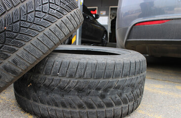 Used tires are piled near a car at a seasonal tire change service
