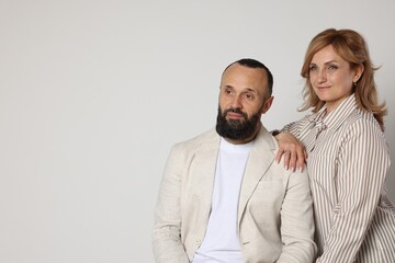 Portrait of lovely couple on light grey background, space for text