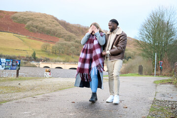 Smiling man with woman covering eyes on country road