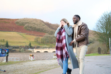 Smiling man with woman covering eyes on country road