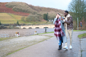 Smiling man with woman covering eyes walking outdoors