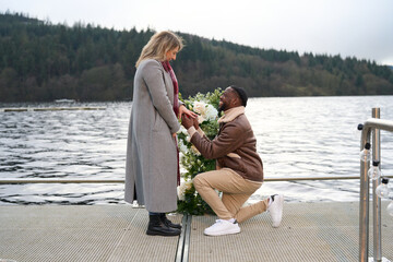 Smiling man proposing marriage to woman on bridge