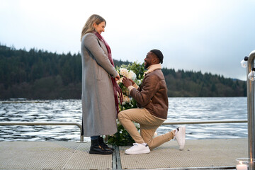 Smiling man proposing marriage to woman on bridge