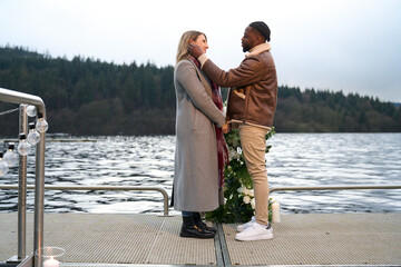 Smiling man proposing marriage to woman on bridge decorated with flowers
