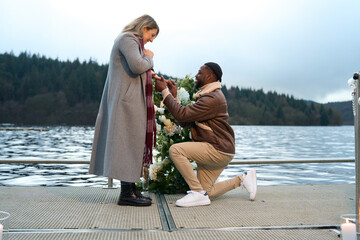 Smiling man proposing marriage to woman on bridge