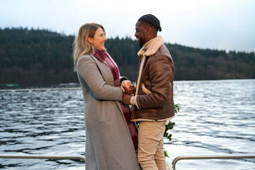 Smiling couple in warm clothing standing face to face on bridge