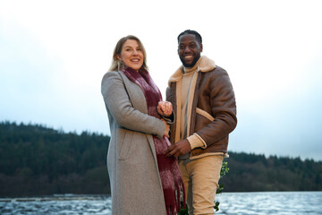 Portrait of smiling couple in warm clothing standing by river