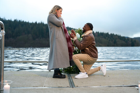 Smiling man proposing marriage to woman on bridge