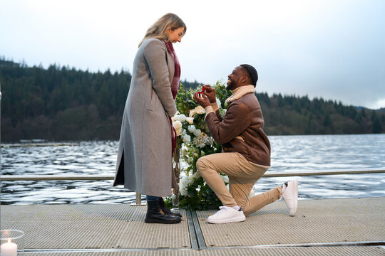 Smiling man proposing marriage to woman on bridge