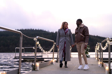 Smiling couple walking on decorated pier at dusk