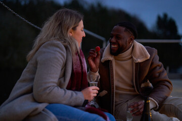 Smiling couple enjoying champagne on pier at dusk