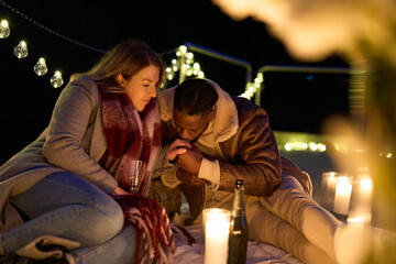 Couple enjoying champagne on pier with candles at night