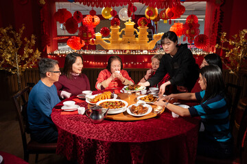 Waitress serving dish to family celebrating Chinese New Year in restaurant
