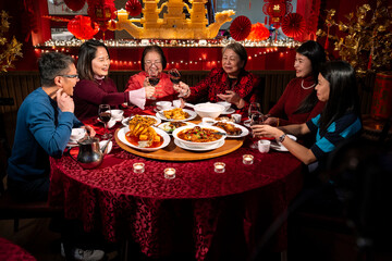 Smiling family toasting with red wine during Chinese New Year dinner