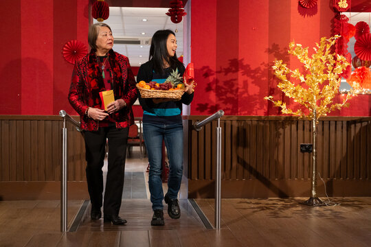 Women with envelopes and basket of fresh fruit entering restaurant