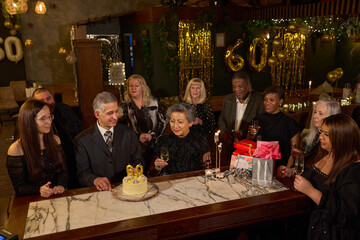 People with birthday cake at 60th birthday party at nightclub