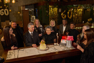 People with birthday cake at 60th birthday party at nightclub
