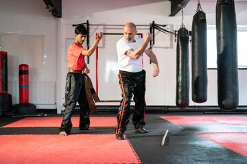 Instructor assisting man practicing kung fu in gym