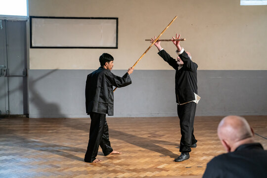 Man with wooden stick undergoing Kung Fu Black Belt test