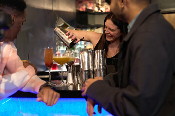 Smiling female bartender preparing cocktail at bar during New Years Eve party