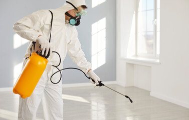 Man from pest control service using spray and insecticide for cleaning home, targeting insect, bug,...