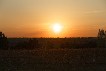 A sun is setting in the sky over a field