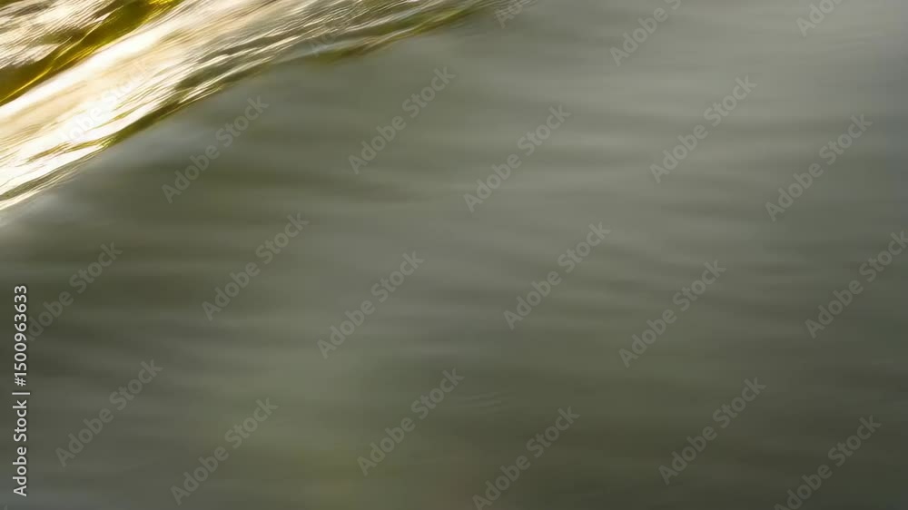 Poster golden light reflecting on ripples across the dark flowing water's surface creating abstract pattern