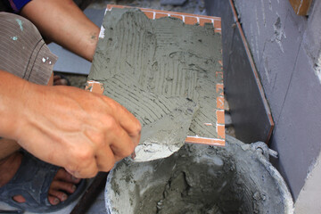 Bricklayer laying mortar on a brick wall at construction site