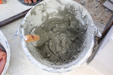 Bucket filled with wet cement and a trowel at construction site