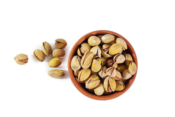 Pile of pistachios in clay bowl isolated on white background. Top view.