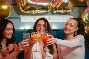 Group of female friends toasting with cocktails during birthday party