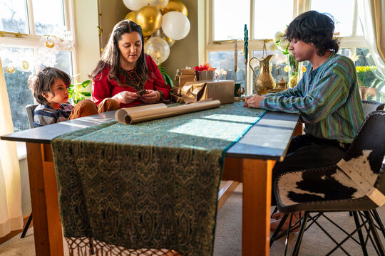 Adult siblings with little sister wrapping gifts for Eid Celebration