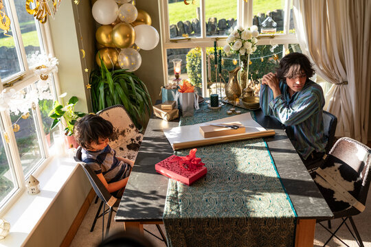Young man with little sister sitting at table and preparing gifts for Eid Celebration