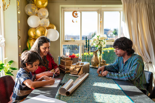 Adult siblings with little sister wrapping gifts for Eid Celebration