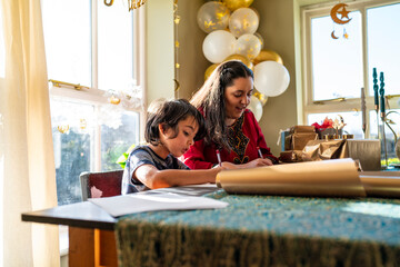 Young woman with little sister wrapping gifts for Eid Celebration