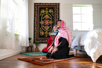 Mother with adult daughter praying during Eid Celebration