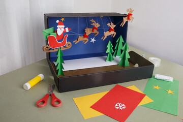 Christmas diorama with Santa sleigh and flying reindeer made from cardboard and paper, ideal for education, DIY content, children crafts, holiday marketing, creative industry use,