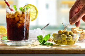 Refreshing cola drink on wooden table with snacks in room