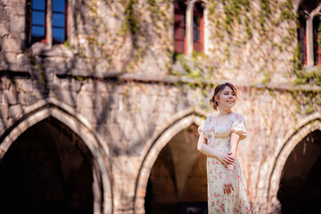 Fototapeta na wymiar Woman in Floral Dress Standing by Historic Stone Building