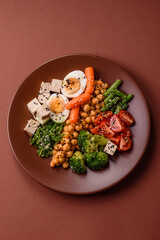 Vegan salad, bowls with chickpeas, broccoli, tomatoes, tofu cheese and boiled eggs