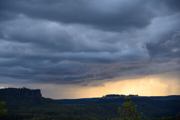 Heavy storm clouds gather over the Saxon Switzerland National Park, Germany, creating a dramatic...