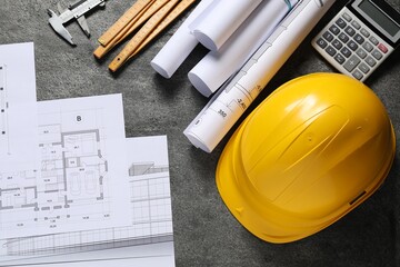 Hard hat, different engineering drawings, folding ruler, calculator and vernier caliper on grey...