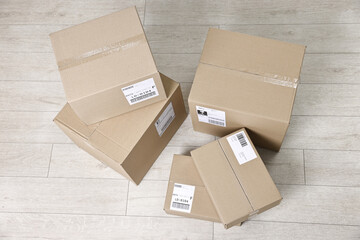 Cardboard parcel boxes with shipping labels on floor indoors, top view