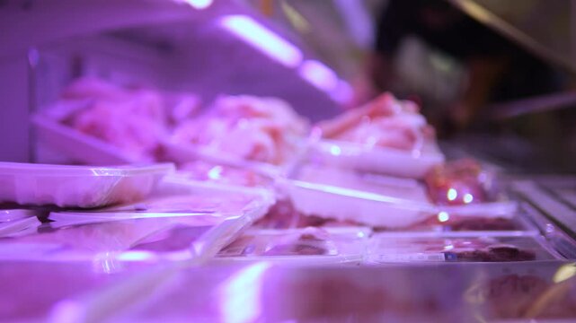 Close-up shopper selecting packaged meat from store shelf. Shelf offers wide range products. Refrigerated shelf provides optimal conditions for meat. Careful selection goods cares about quality food.